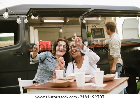 Adult women taking selfie near food truck