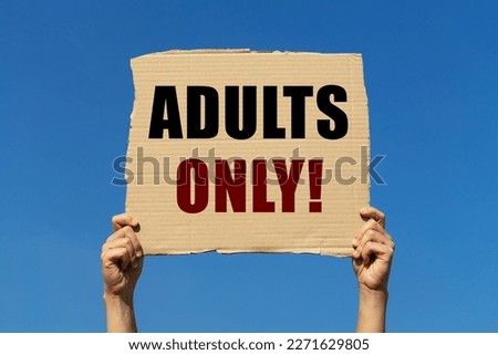 Adults only text on box paper held by 2 hands with isolated blue sky background. This message board can be used as business concept about adults only content.