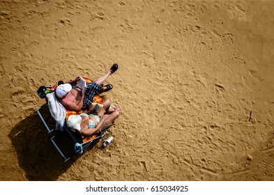 Adults resting and reading a book on a beautiful clean beach shot from the top offrom above