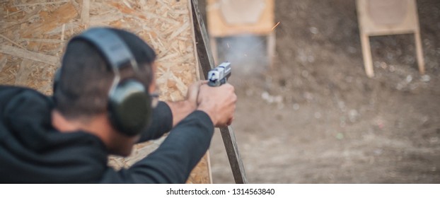 Advanced outdoor tactical shooting on target around barrier and wall. Civilian firearm safety training on shooting range