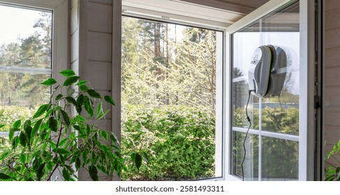 Advanced window cleaning robot operating on home window. Spring cleaning and home cleaning, cleaning services or DIY, spring mood. For modern homes, effortless maintenance, safety, and time-saving