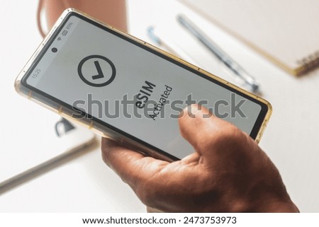 Advantage of embedded SIM connection for network services concept. A person's mobile phone displaying eSIM activated successfully.