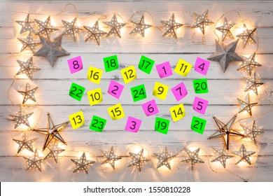 Advent Calander Parer Notes, With A Border Of Golden Star Christmas Lights, On A Distressed White Wooden Board