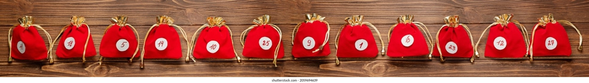 Advent calendar. Red bags with gifts on a wooden background.