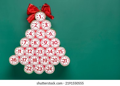 Advent calendar in shape of Christmas tree with numbers and ribbon instead of star on red table Xmas advent calendar concept Top view Flat lay Holiday card