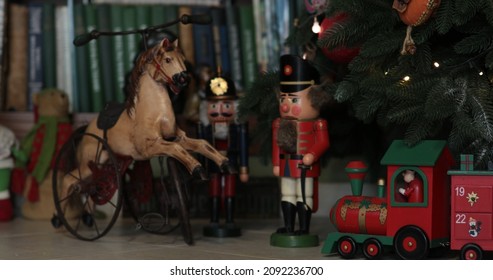 Advent Calendar In Shape Of Wooden Red Santa Train Under Christmas Tree Decorated With Retro Christmas Ornaments. Antique Nutcracker Soldier Toy And Doll Horse Under Artificial Fir Tree