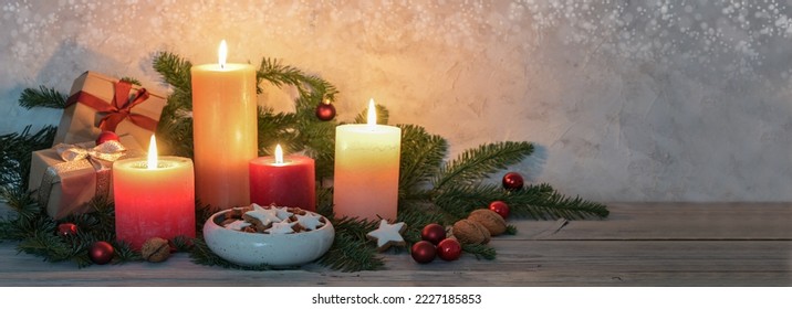 Advent candles in warm colors, cinnamon stars, Christmas decoration and fir branches on a rustic wooden table, panoramic format, copy space, selected focus, narrow depth of field - Powered by Shutterstock