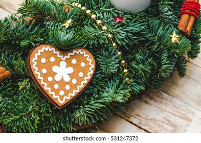 Advent Christmas wreath made natural pine with Heart shaped gingerbread cookie, red decorations, cinnamon stick, gold beads, star confetti on rustic wooden background. Catholic Xmas concept. - Powered by Shutterstock