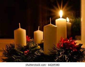 Advent wreath with a lighted candle placed on the window