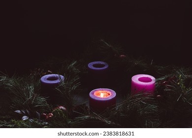 Advent wreath with one candle lit in a dark room