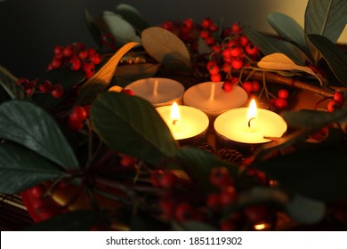 advent wreath with red berries, two lighted candles