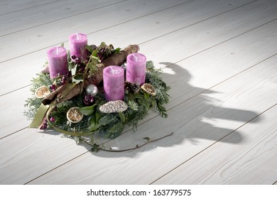 Advent wreath of twigs with purple candles and various ornaments