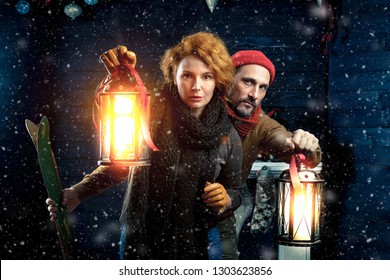 Adventure. Alert Couple With Bright Hand Lanterns Playing Quest Together While Searching For Prompts In Wooden House With Christmas Decorations