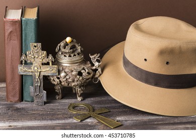 Adventure and archeological concept for lost artifacts with hat, vintage books, iron vase, key of life, vintage cross on wood table