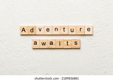 Adventure Awaits Word Written On Wood Block. Adventure Awaits Text On Cement Table For Your Desing, Concept.