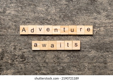 Adventure Awaits Word Written On Wood Block. Adventure Awaits Text On Cement Table For Your Desing, Concept.