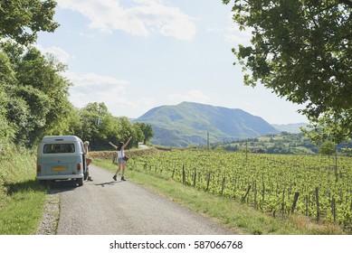 Adventure Girl Friends On Road Trip Vintage Camper Van Driving Through Countryside Vineyards Arms Outstretched