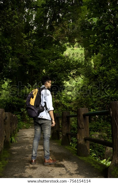 Adventure man hiking wilderness mountain with
backpack, outdoor lifestyle survival vacation. Hiker on the old
wooden bridge.