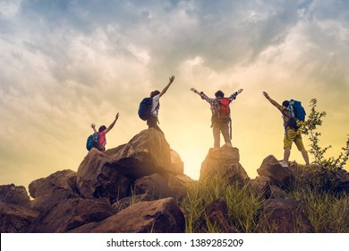 Adventure to overcome the limits of life, male and female hikers climbing up mountain cliff under sunrise. they are success full at top the mountain. helps and team work concept. 