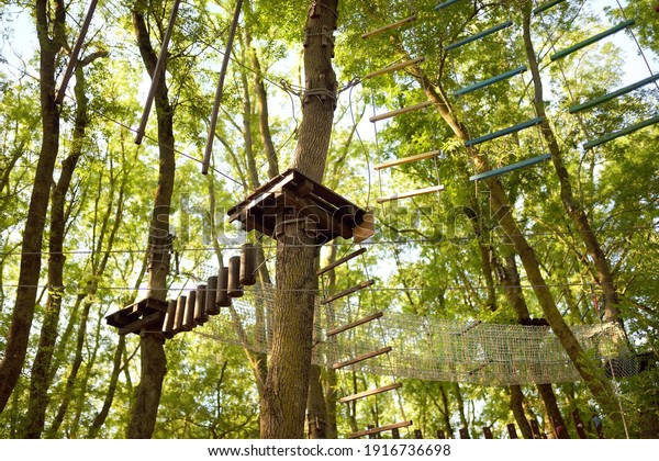 Adventure Park for\
children - ropes, stairs, bridges in woods among tall trees.\
Climbing park, adventure playground in the forest. Activity\
entertainment for family with\
kids