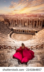 Adventure photo tourist woman in red dress on background Amphitheater in Hierapolis ancient city Pamukkale Turkey.