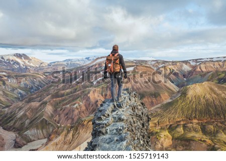 adventure travel, hiking in Iceland with backpack, tourist looking at colorful landscape of Landmannalaugar