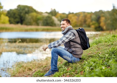 adventure, travel, tourism, hike and people concept - smiling man with backpack resting on river bank - Powered by Shutterstock
