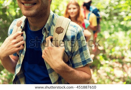 adventure, travel, tourism, hike and people concept - close up of friends walking with backpacks in woods