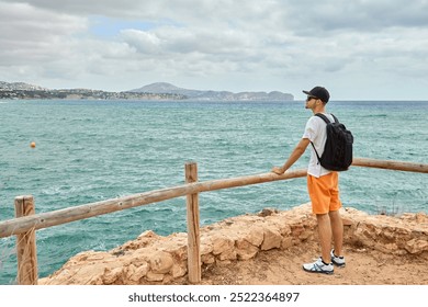 Adventure Traveler on Cliff Edge Enjoying Breathtaking Ocean View in Spain with Blue Skies and Rocky Coastline. Idyllic Mediterranean Seascape Rugged Coastline Turquoise Waters Calpe Spain Hot Summer - Powered by Shutterstock