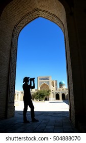 Adventurer (Indiana Jones Look) Photographer In The Inner Courtyard Of The Kalyan Mosque, Part Of The Po-i-Kalyan Complex In Bukhara, Uzbekistan.