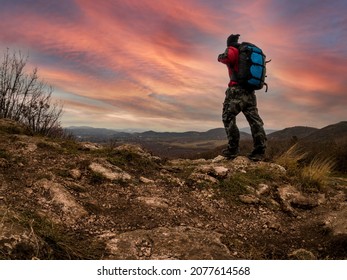 Adventurer man with back pack on mountain top at dramatic sunrise