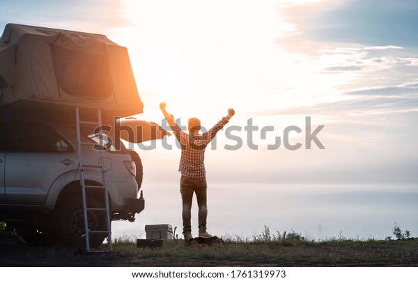 adventurer man in journey travel\
with off road car and roof tent to enjoy freedom and explorer\
concept. discover the world living near the power of the nature.\
