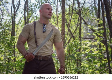 Adventurer Man With A Machete Knife In The Hands In The Forest.