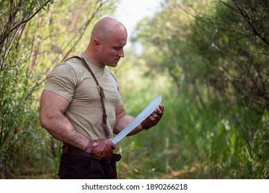 Adventurer Man With A Machete Knife In The Hands In The Forest.