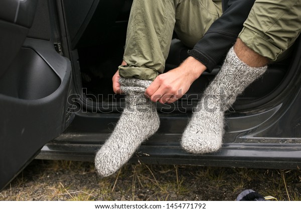 Adventurer, touirst or hiking affectionate\
changes shoes inside car after or before long wet walk in harsh\
conditions. Puts on pair or clean and dry wool socks to warm up\
feet in cold\
weather
