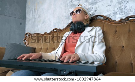 adventures of strange people. funny pathetic woman dj writes music with laptop and midi keyboard.