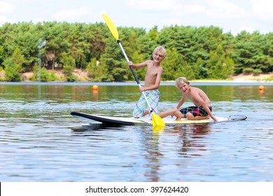 Adventurous boys learning to paddle on stand up board. Happy children, teenage schoolboys, having fun enjoying adventure experience on the river or lake on a sunny day during summer holidays - Powered by Shutterstock