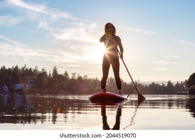 Adventurous Caucasian Adult Woman Paddling On A Stand Up Paddle Board In Water At A City Park. Sunny Sunset Sky. Gorge Park, Victoria, Vancouver Island, BC, Canada.