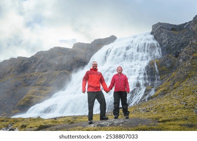 Adventurous Couple in red rain jackets enjoying Dynjandi Waterfall, Westfjords, Iceland. - Powered by Shutterstock