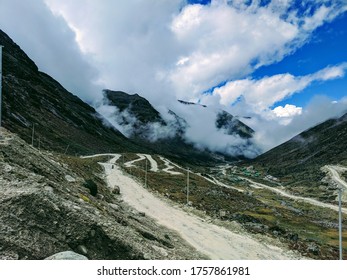 An Adventurous Curvey Road In Between The Mountains Over A Cloud Backdrop.. 