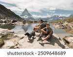 Adventurous family and their dog enjoying the beauty of the mountains by a lake and with the Matterhorn peak in the background