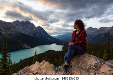 Adventurous girl sitting on the edge of a cliff overlooking the beautiful Canadian Rockies and Peyto Lake during a vibrant summer sunset. Taken in Banff National Park, Alberta, Canada. - Powered by Shutterstock