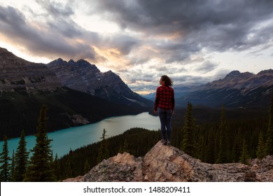 Adventurous girl standing on the edge of a cliff overlooking the beautiful Canadian Rockies and Peyto Lake during a vibrant summer sunset. Taken in Banff National Park, Alberta, Canada. - Shutterstock ID 1488209411