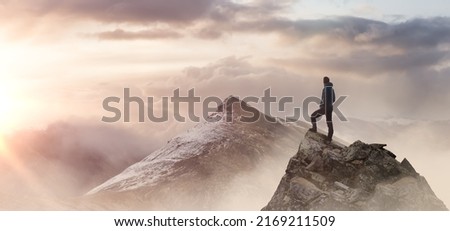 Adventurous Man Hiker standing on top of icy peak with rocky mountains. Adventure Composite. Aerial Background Image of landscape from Yukon, Canada. Sunset Sky