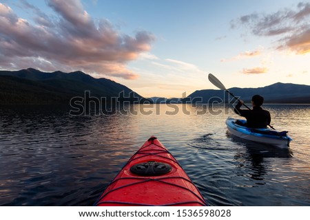 Adventurous Man Kayaking in Lake McDonald during a sunny summer sunset with American Rocky Mountains in the background. Taken in Glacier National Park, Montana, USA.