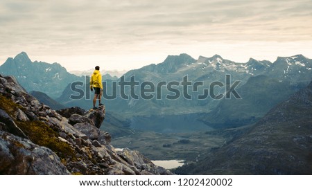 
Adventurous man is standing on top of the mountain and enjoying the beautiful view during a vibrant sunset. Beautiful Nature Norway natural landscape aerial photography
