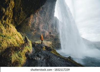 Adventurous man standing under the waterfall, The Seljalandsfoss waterfall in the southern part of Iceland