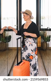 Adventurous Mature Woman, Arriving At The Hotel Room From Her Summer Holiday. Woman Unpacking Her Luggage In The Dressing Room.