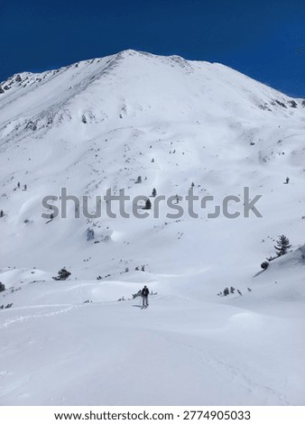 Adventurous ski tourer exploring untouched alpine terrain in Pirin National Park with dramatic snowy peaks all around.
