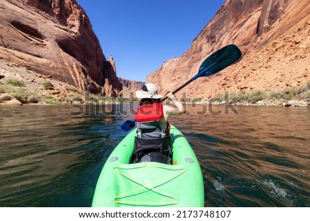 Adventurous Woman on a Kayak paddling in Colorado River. Glen Canyon, Arizona, United States of America. American Mountain Nature Landscape Background. Adventure Travel